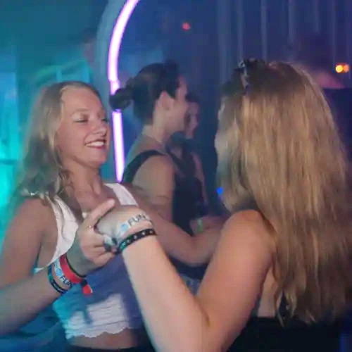 Zwei weibliche Jugendliche feiern in einer Disco.